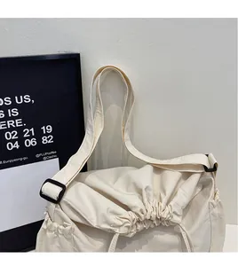 Detail of cream canvas crossbody bag featuring smooth adjustable strap and drawstring closure