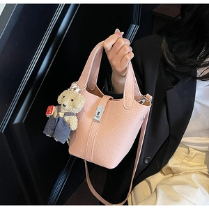 Pink lychee grain leather bucket bag featuring a cute teddy bear charm and silver buckle