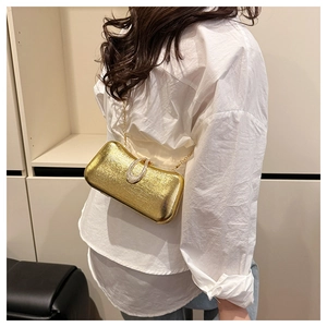 Detail of gold evening clutch bag with brushed metal texture and rhinestone ring clasp
