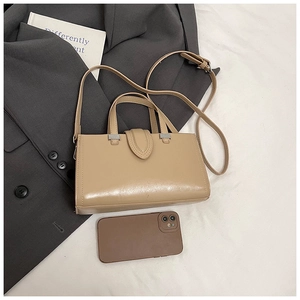 Détail d'un sac carré beige avec poignée et bandoulière réglable sur veste de costume