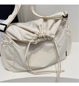 Detail of off-white canvas crossbody bag showing drawstring closure and wide strap
