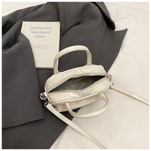 Top view of cream white PU leather crossbody bag showing interior and zipper closure