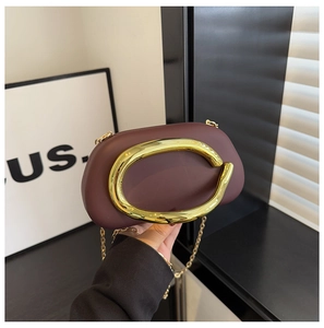 Detail of dark red semi-circular bag with golden C-handle and metallic chain strap