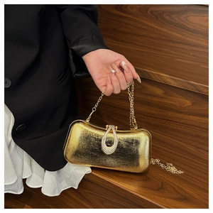 Close-up of gold evening clutch with crystal teardrop clasp and chain shoulder strap