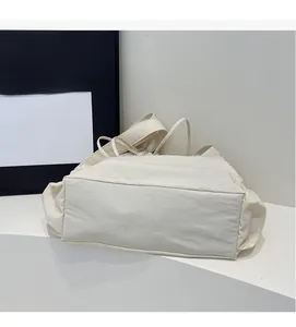Detail of spacious beige canvas tote bag showing wide base and soft pleated texture