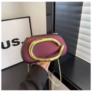 Close-up of a burgundy evening clutch bag with a large gold metal frame and chain strap