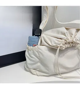 Detail of canvas shoulder bag with functional drawstring side pocket holding a blue umbrella