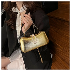 Detail of gold evening clutch with teardrop rhinestone clasp and metallic finish
