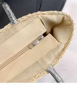 Detail view of woven straw bag featuring silver hardware zipper and refined inner lining
