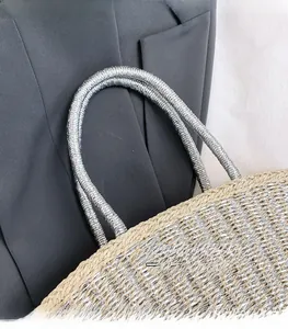 Detail of silver metallic woven straw handbag showing intricate texture and cord handle