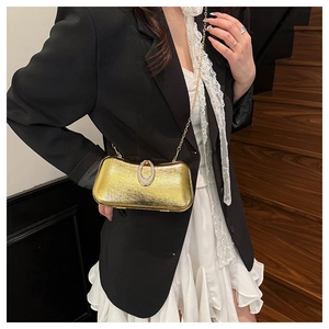 Detail of gold metallic clutch bag with rhinestone buckle and fine chain strap on stairs