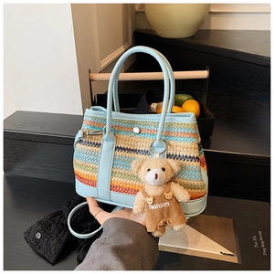 Détail d'un sac à main tissé rayé avec bordure en cuir bleu et breloque ours en peluche