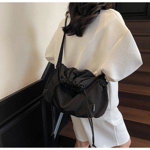 Detail of black drawstring crossbody bag featuring water-resistant fabric and fashion label