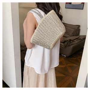 Chic woven straw crossbody bag with silver chain strap shown in a cozy home setting