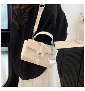 Détail du sac en paille tressée avec bandoulière large et mini pendentif décoratif chic
