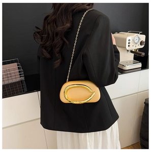 Detail of yellow leather crossbody bag with gold horseshoe buckle worn by a model