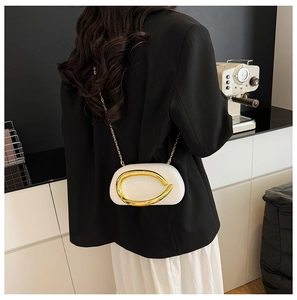 Close-up of a white luxury chain bag with gold sculptural buckle and metal strap