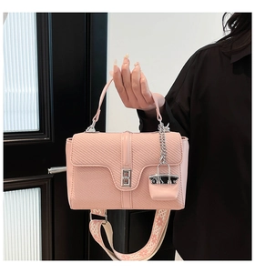 Détail du sac bandoulière rose avec rabat tissé et large bandoulière à motifs géo