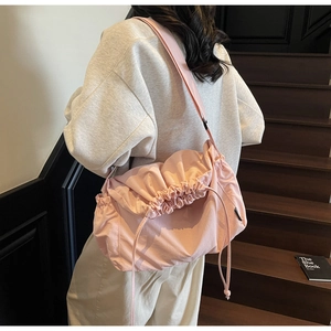 Detail of pink nylon drawstring crossbody bag shown on model for casual daily use