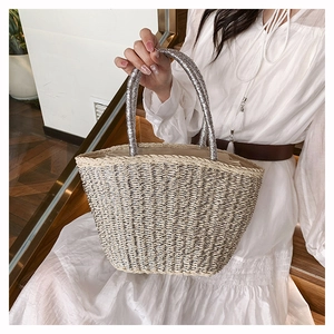 Detail of woven straw tote bag with sparkling silver sequin handles and minimalist design