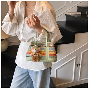 Détail du sac tressé coloré avec poignées en cuir vert clair et pendentif d'ours