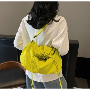 Detail of high-capacity neon yellow drawstring crossbody bag worn over the shoulder