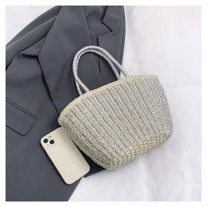 Close-up of woven tote bag texture with metallic threads and cylindrical handle detail