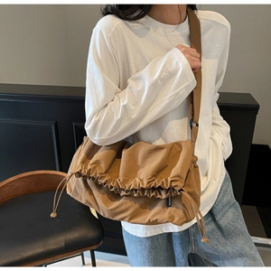 Detail of a brown canvas crossbody bag featuring a drawstring closure and fashion label