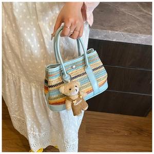 Détail du sac cabas tissé à rayures multicolores avec bordure en cuir bleu clair et pendentif