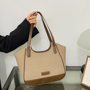 Bolso tote de lona con adornos de cuero y correas dobles en un ambiente interior elegante