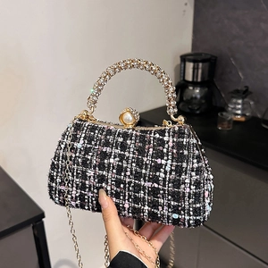 Black and white tweed handbag with rhinestone handle and pearl clasp carried by hand