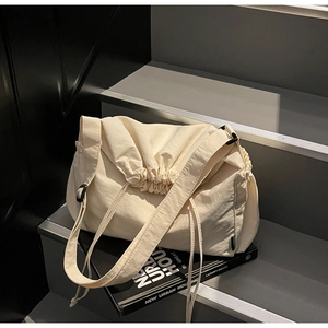 Detail of off-white canvas crossbody bag with drawstring closure and fashion label