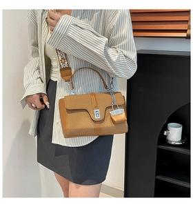Détail du sac bandoulière marron avec rabat tressé et large sangle aux motifs géométriques