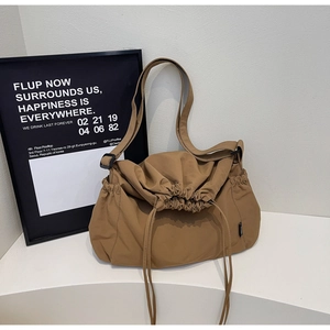 Detail of khaki drawstring tote bag featuring adjustable shoulder strap and side pockets