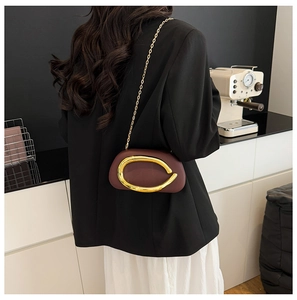Detail of burgundy vintage crossbody bag with large gold buckle and chain strap