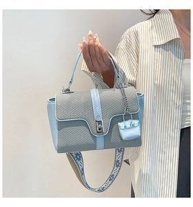 Détail du sac bandoulière bleu clair avec sangle brodée et fermoir rotatif