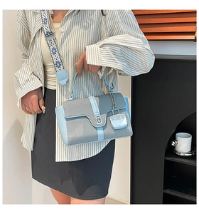 Détail du sac à bandoulière tissé bleu avec sangle brodée porté par un modèle