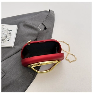 Macro view of matte red clutch bag with golden handle and black fabric lining