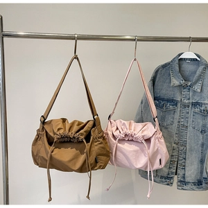 Detail view of large nylon drawstring shoulder bags in brown and pink on a hanger