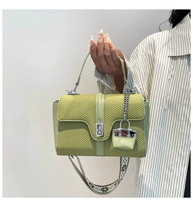 Détail du sac bandoulière vert texturé avec fermoir rotatif argenté et sangle large