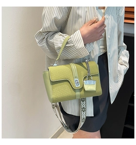 Détail du sac bandoulière vert clair avec texture tissée et large sangle à motifs