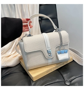 Gros plan d'un sac à main blanc tissé avec fermoir argenté et bandoulière large mode