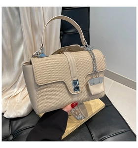 Détail du sac beige en texture tissée avec fermoir argenté et bandoulière large brodée