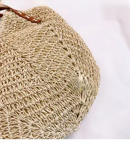 Close-up of hollow straw weave texture and brown leather strap on minimalist shoulder bag