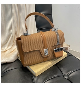 Détail d'un sac en cuir PU marron avec texture tressée, fermoir métal et bandoulière ethnique