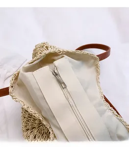 Close-up of beige woven straw bag featuring silver metal zipper and soft fabric lining