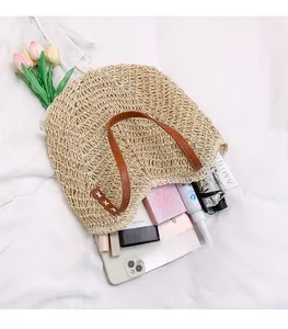 Beige woven straw shoulder bag showing spacious interior with daily essentials and leather strap