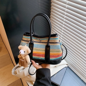 Sac à main tissé à rayures chic avec pendentif ours et poignées en cuir par mannequin
