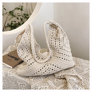 Detail of a beige crochet tote bag with woven hollow patterns and tassel decoration