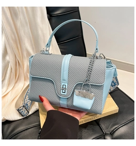 Détail du sac à main bleu clair avec bandoulière tissée et fermoir rotatif en argent